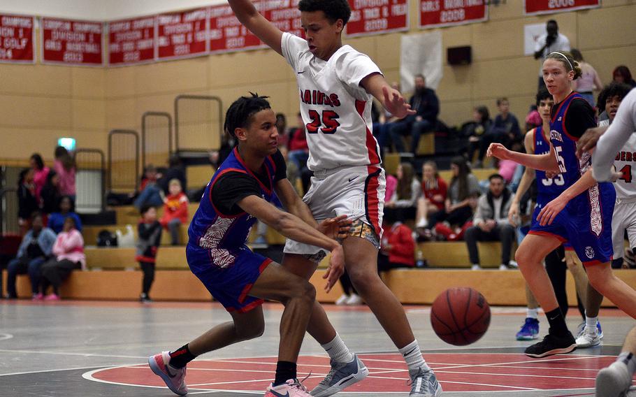 Ramstein's Christian Roy passes the ball into the low block as Raider Jason Quarles defends during a Jan. 31, 2024, game at Kaiserslautern High School in Kaiserslautern, Germany.