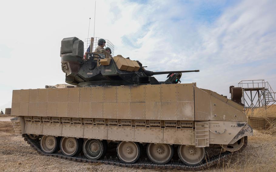 Two soldiers sit in the turret of a M2A3 Bradley Fighting Vehicle.