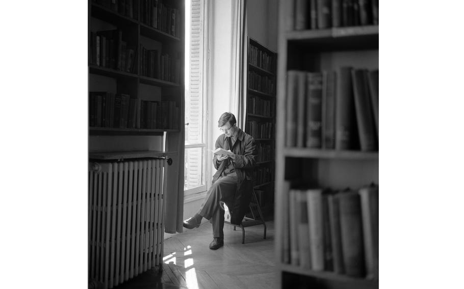 A patron sits on a stepstool and reads a book