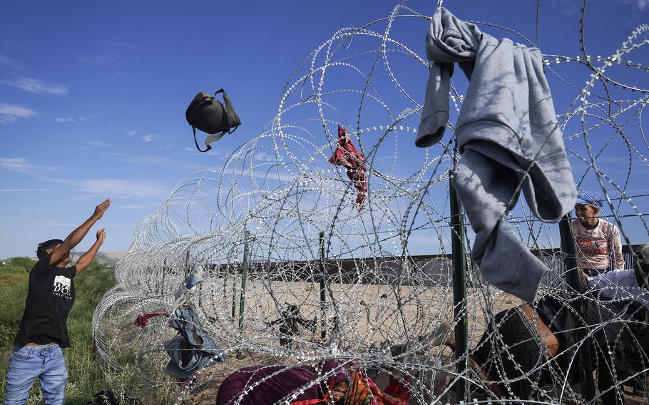 A Venezuelan migrant tosses a backpack over the razor wire near the U.S.-Mexico border on Thursday, Sept. 21, 2023, in Ciudad Juárez. 