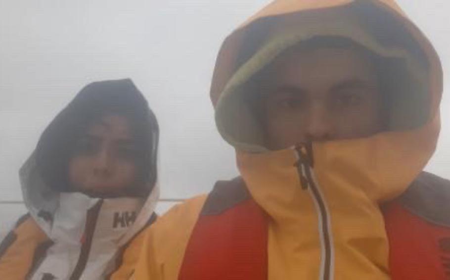 Tyler Savage and Bella Siegrist pose for a selfie while bundled up for the chilly first leg of their San Diego-to-Honolulu trip via sailboat from May 15 to June 5, 2021.