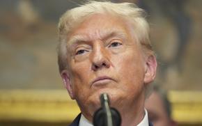 A closeup of President Donald Trump’s face, with an out-of-focus microphone obscuring part of his chin and neck.