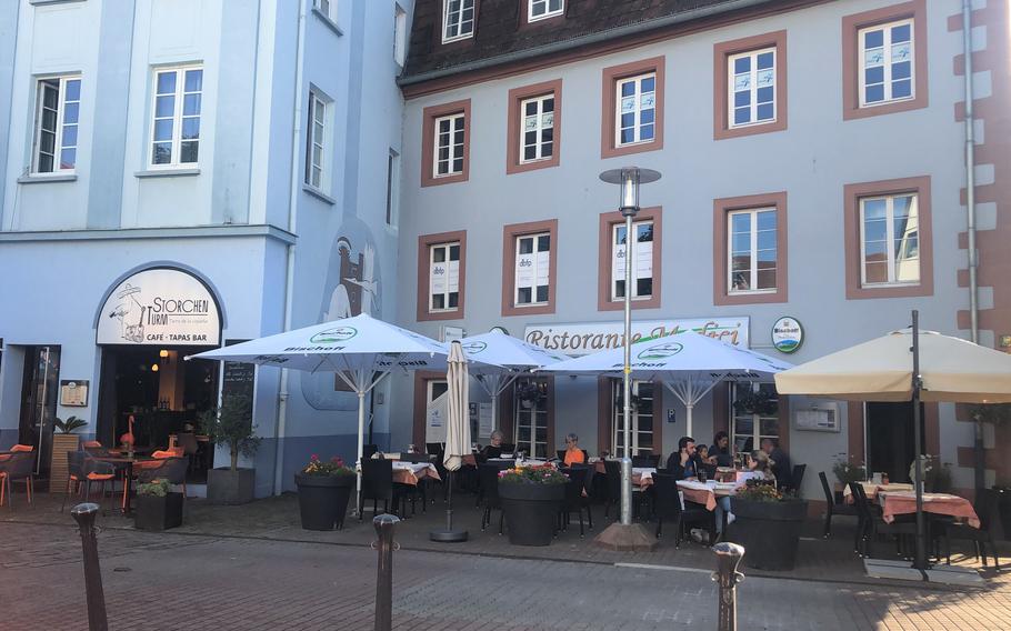 People eat outside near the market square in Kaiserslautern, Germany. Under new coronavirus rules in the state of Rheinland-Pfalz, shops and restaurants will be allowed to stay open when COVID-19 numbers rise above certain levels.