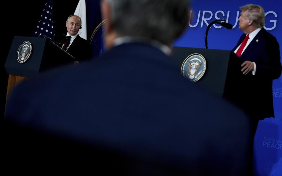 President Donald Trump stands at a presidential podium on the right while Russia’s President Vladimir Putin speaks at another presidential podium on the left during a news conference at Joint Base Elmendorf-Richardson in Anchorage, Alaska. Both podiums display the presidential seal, with American and Russian flags visible in the background