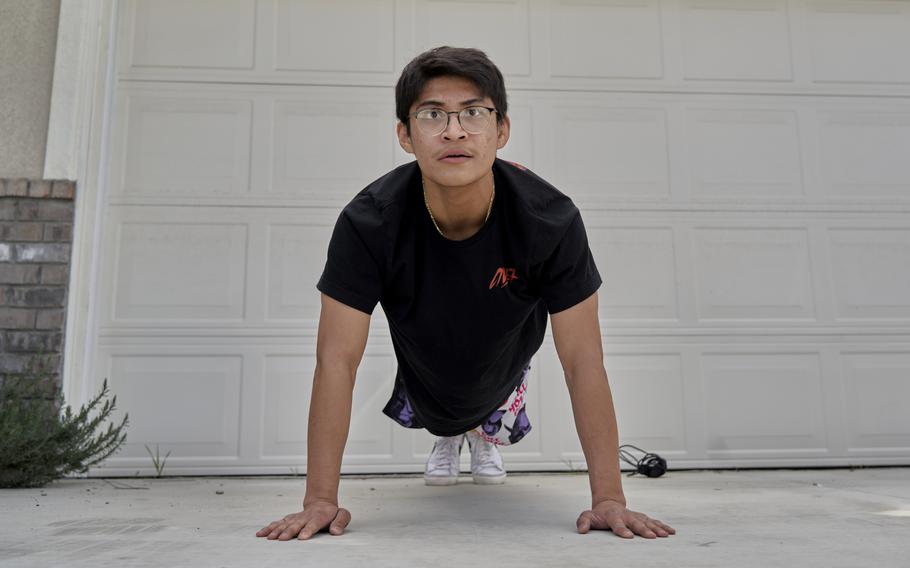 Erik Suarez del Solar does push-ups in the family's driveway as part of his training to become a firefighter. At 21, he's older than his father at the time of his death. 