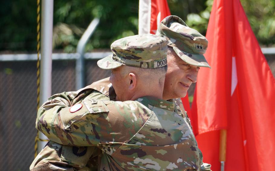 Brig. Gen. James Dooghan hugs Maj. Gen. Dave Womack during an outdoor ceremony.