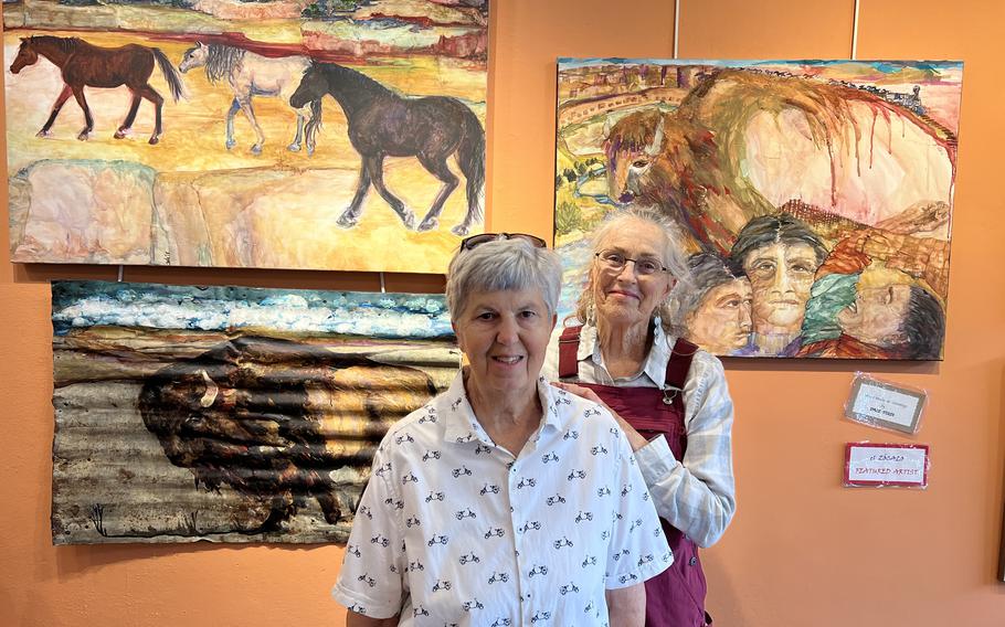 Meredith Britt, left, and Dale Tozzi are two of the artists of El Zocalo Cooperative Art Gallery on Plaza Park in Las Vegas, N.M.. Behind them is some of Tozzi’s work. 