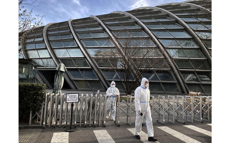 Security wears PPE to protect against the spread of COVID-19 as they guard outside an office building on December 11, 2022, in Beijing, China.