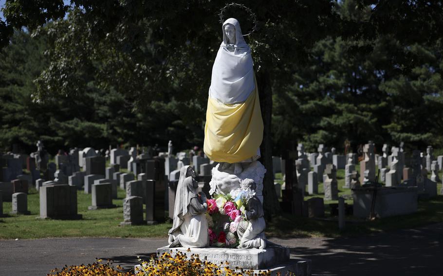 A statue of Mary wearing a faded Ukrainian flag is seen near the entrance of St. Mary’s Ukrainian Cemetery in Elkins Park.