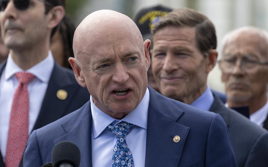 Mark Kelly speaks into a microphone while standing in front of rally-goers.
