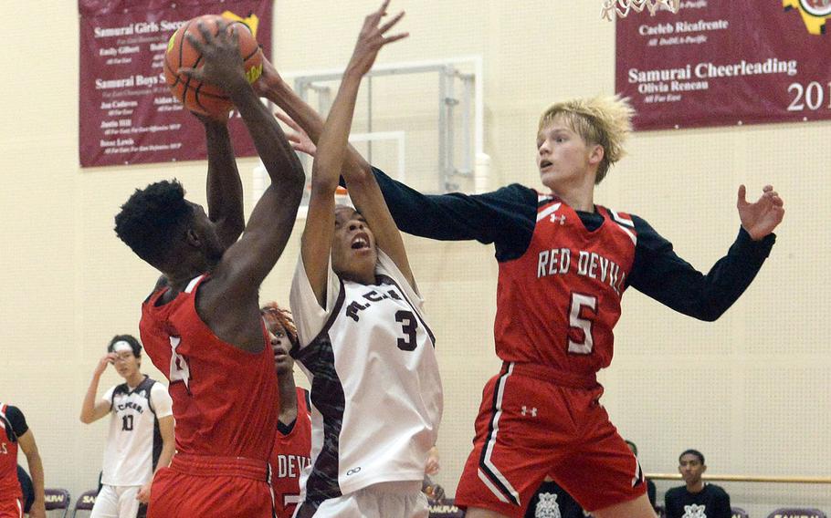 Nile C. Kinnick's Kennedy Hamilton and teammate Gregor Tolar battle Matthew C. Perry's Billy Hill for a rebound during Friday's DODEA-Japan boys basketball game. The Red Devils won 67-29.