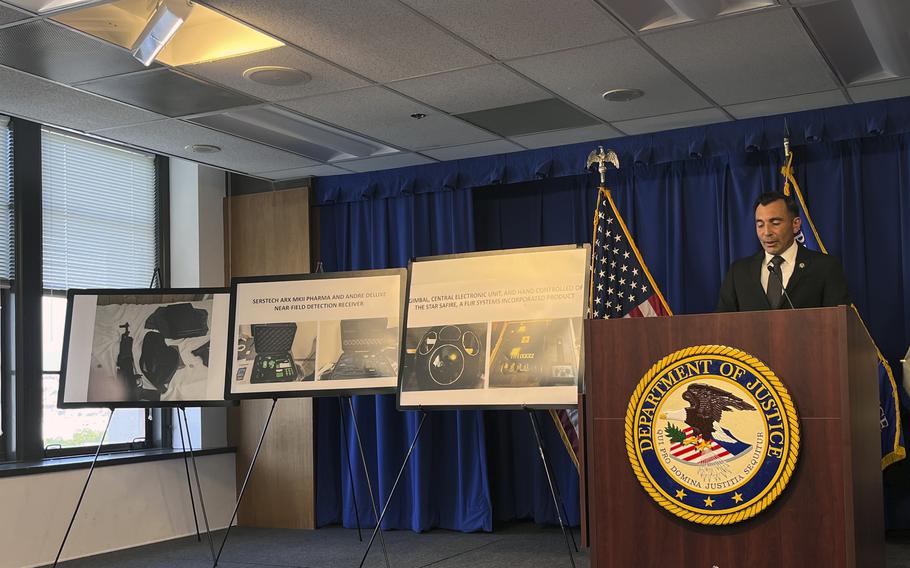 A man speaks from behind a podium next to black and white images displayed on easels. 