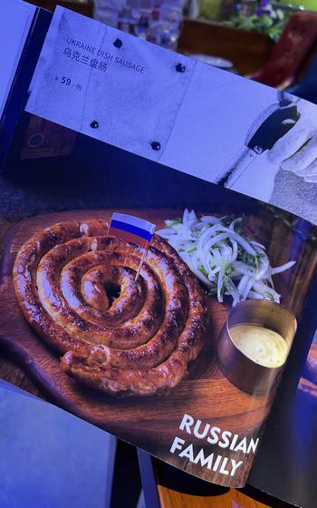 A restaurant menu in Heihe, China, near the China-Russia border, features "Ukraine dish sausage," with a photo of a sausage with a Russian flag on it on June 15, 2022. 