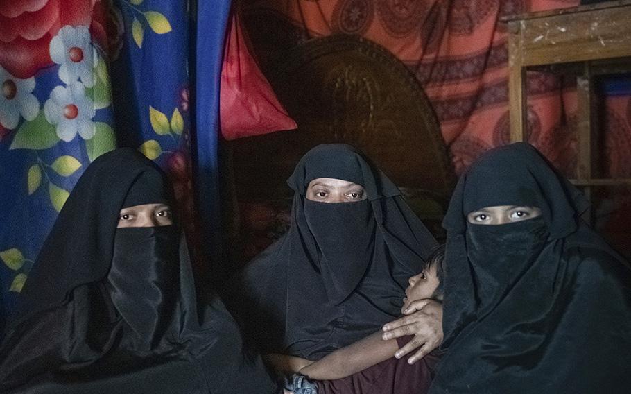 Baher holds her son and poses for a portrait inside her shelter at a refugee camp in Cox’s Bazar with her two daughters, Ismotara, 17, on left, and Jannatara, 15, on right.