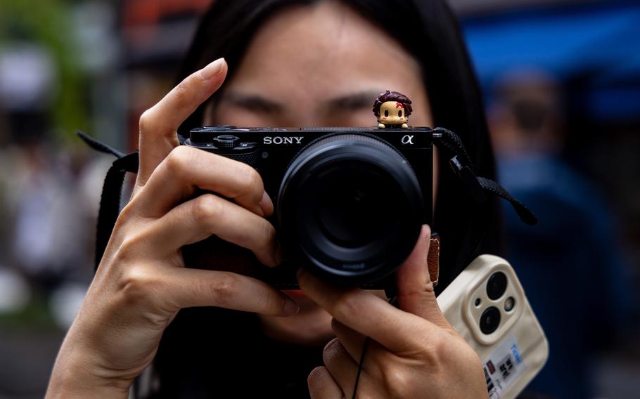 A woman holds a digital camera to her eye to take a photo.