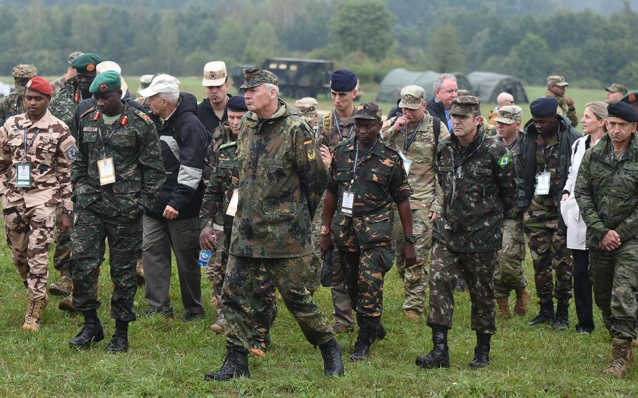 Military leaders from various countries participating in the U.S. Army-led African Land Forces Colloquium walk through the field Sept. 14, 2022, at the Vilseck training area, where they watched soldiers from the 2nd Cavalry Regiment test for the Expert Infantryman Badge.