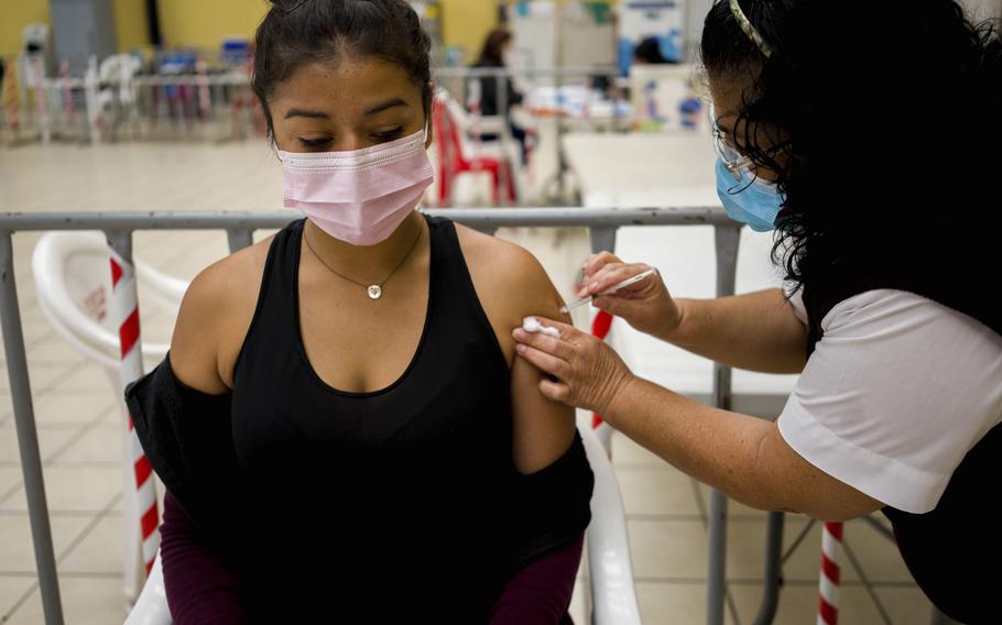 A healthcare worker administers an AstraZeneca booster shot for COVID 19 at a vaccination center in Guatemala City, Tuesday, March 1, 2022.  (AP Photo/Moises Castillo)