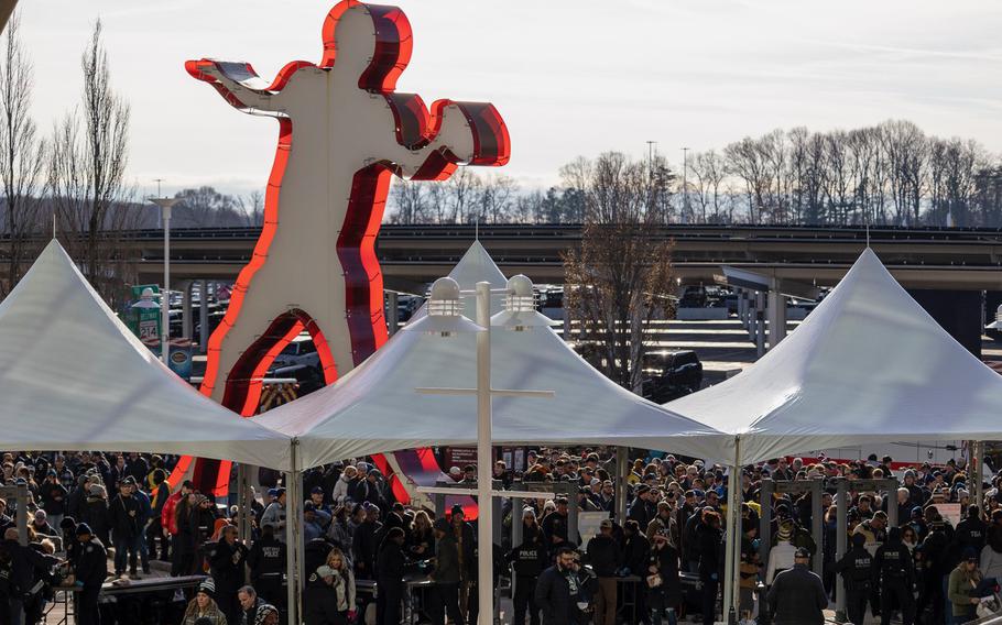 A large figure of a football player towers over crowds entering the stadium.