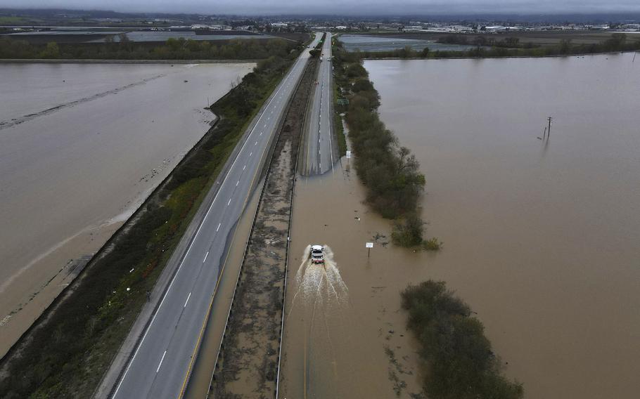 A CalTrans vehicle drives north through floodwaters that closed state Highway 1 at the Santa Cruz County line in California, Sunday, March 12, 2023. 