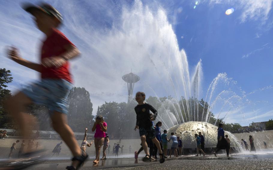 The International Fountain at Seattle Center is packed with children as they run from the water that is showering on them Wednesday, July 27, 2022 in Seattle. 