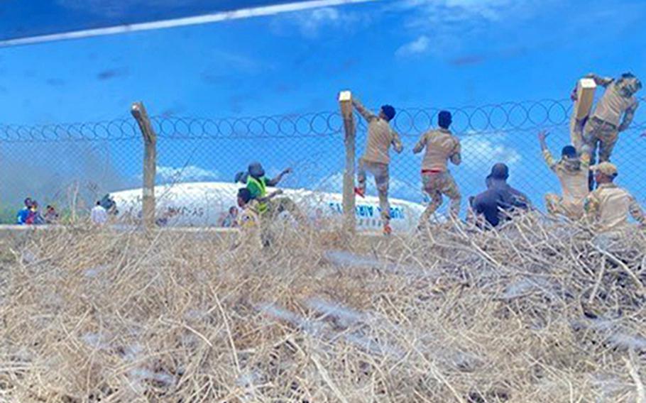 Somali commandos climb a fence to get to a Jubba Airlines plane that crash-landed July 18, 2022, at Mogadishu International Airport. Three U.S. soldiers were conducting medical training with the commandos at the time, and they joined rescue efforts. No one was killed in the crash, Somali officials said.