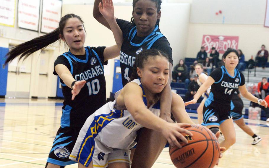 Yokota's Coco Jones gets hemmed in by Osan's Jonessa Jones and Tatiana Lunn. The Panthers edged the Cougars 44-40.