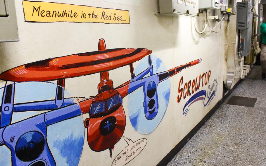 Wall art in a hallway of the USS Dwight D. Eisenhower shows a surveillance C-2 Hawkeye plane. In reference to the Houthi attacks, the art reads: “Meanwhile in the Red Sea... multiple unmanned aerial vehicles (UAVs) tracking south.”
