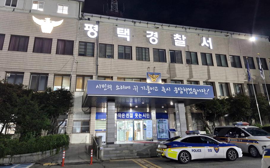 Night view of a Korean police station building with Korean text signage. Two Korean police cars are parked in front of the illuminated entrance. 