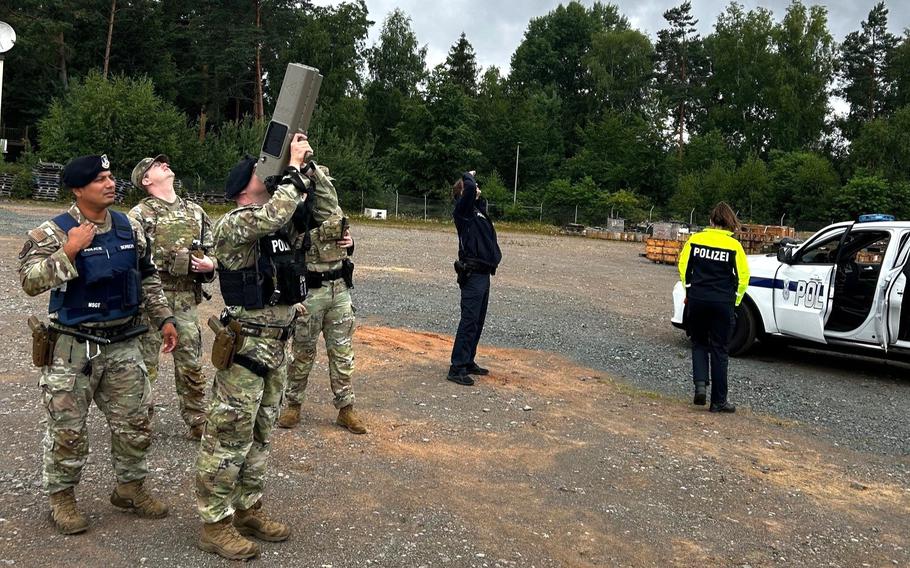 A soldier points a device into the sky.