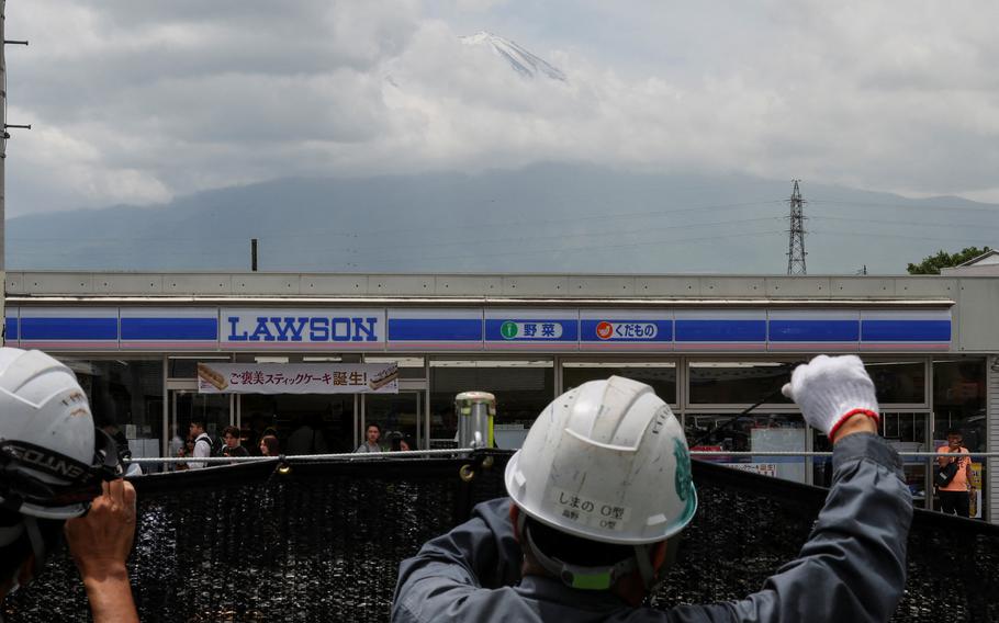 Workers build a barrier to block the view of a popular Mount Fuji photo spot, near a convenience store in Fujikawaguchiko town, Yamanashi prefecture, Japan, May 21, 2024. 