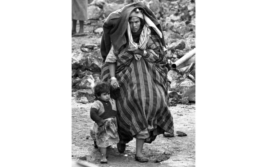 Carrying all the belongings she could save from her ruined home, a mother leads her child in search of shelter following an earthquake, in Barce, Libya, in February 1963. Most of the ancient city of Barce was destroyed in the magnitude 5.6 earthquake on Feb. 21, 1963. The final death toll was some 300 people with another 500 injured.