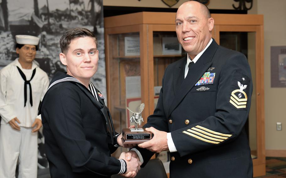 Petty Officer 1st Class Cayla George, assigned to the Naval Air Station Sigonella public works department, receives the Seabee Memorial Scholarship Association's 2023 Everyday Hero Award from Senior Chief Petty Officer Marc Comaduran at the Naval Construction Battalion Center in Gulfport, Miss., on Nov. 16, 2023. The award was created to recognize Seabees for heroic actions, on or off duty.