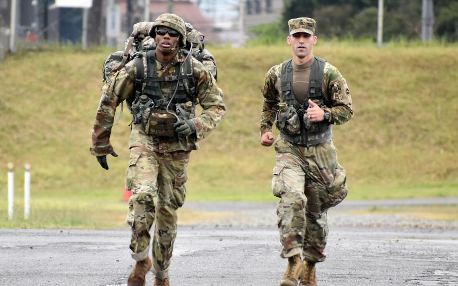 Sgt. Jamal Walker, left, a drummer for the U.S. Army Japan Band, nears the finish line of the 12-mile ruck march during a Best Warrior competition at Sagami General Depot, Japan, May 13, 2021. Walker came in first in the ruck march and also won the competition’s noncommissioned officer category. 