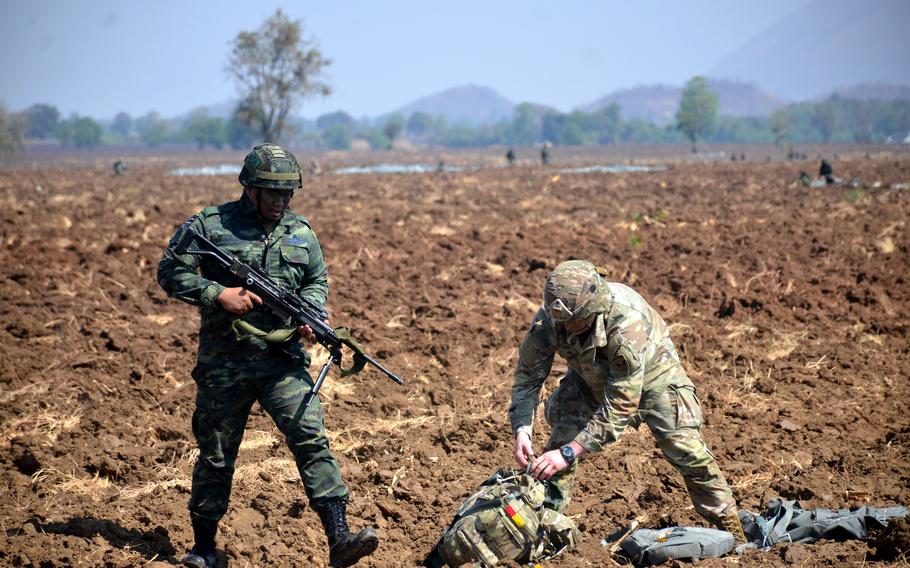 Thai and U.S. soldiers check on each other after parachuting from an Air Force C-17 during the Cobra Gold exercise in central Thailand, March 5, 2024.