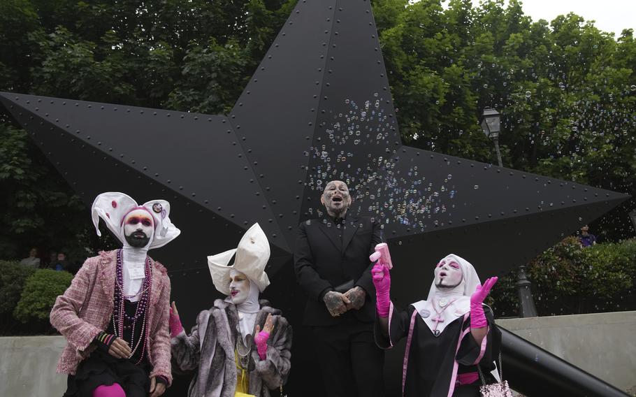 French citizens stand in front of a memorial for the LGBTQ+ individuals of the holocaust.
