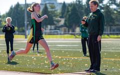 Robert D. Edgren senior Morgan Erler crosses the finish line in 18 minutes, 51.4 seconds as Eagles coach Tim Schwehr casts an eye on the time.