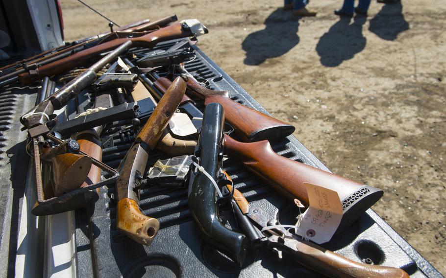 ATF agents stand near a pickup truck bed with seized and purchased guns at a scrap yard in Western Maryland in 2013.