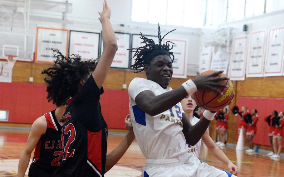 Yokota's Jai Bailey snags a rebound in front of E.J. King's Kenji Wooten during Saturday's DODEA-Japan boys basketball game. The Panthers won 67-57.