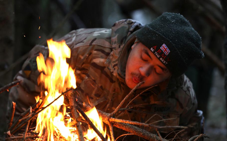 A soldier from the United Kingdom, with enhanced Forward Presence Battle Group-Poland, breathes air into a fire during a cold-weather survival course in December 2020 at Bemowo Piskie Training Area, Poland. The U.K. and Estonia have sent troops to Poland to help the country deal with a migrant crisis on its border.