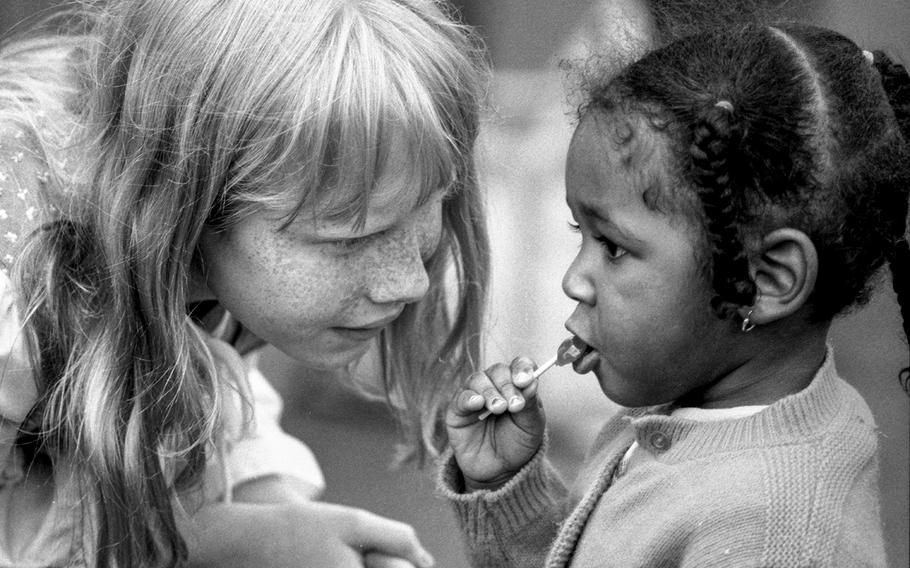A woman talks to a young child eating a lollipop