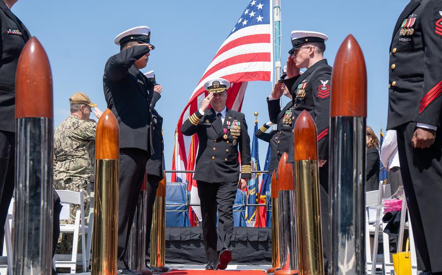 A U.S. flag can be seen in the background Capt. Justin Harts walks through a line of saluting service members. 