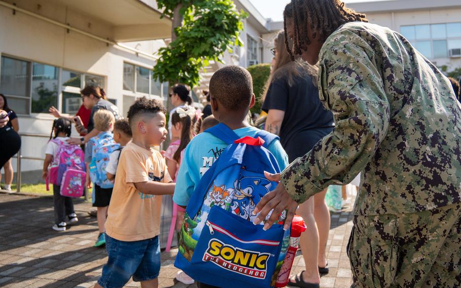 A soldier ushers her child forward. He’s wearing a Sonic the Hedgehog backpack.