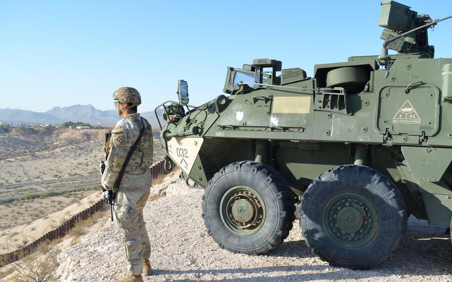 Soldier stands next to a military vehicle as he looks over open land at the southern border.
