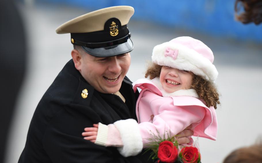 A chief petty officer serving aboard the Virginia-class submarine USS Minnesota embraces his child during a homecoming event at Naval Submarine Base New London in Groton, Conn., Nov. 26, 2021. Sailors who are designated secondary caregivers now qualify for up to three weeks of paid parental leave after the birth or adoption of a child, the Navy said this week. 