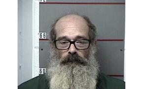 Mugshot of Gregory Heimann wearing glasses, balding and with a long beard.