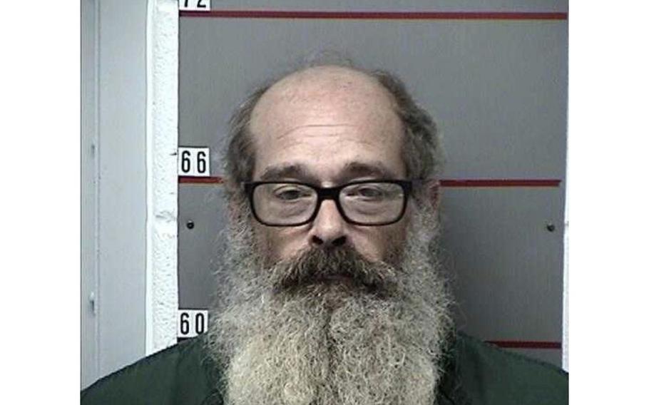 Mugshot of Gregory Heimann wearing glasses, balding and with a long beard.