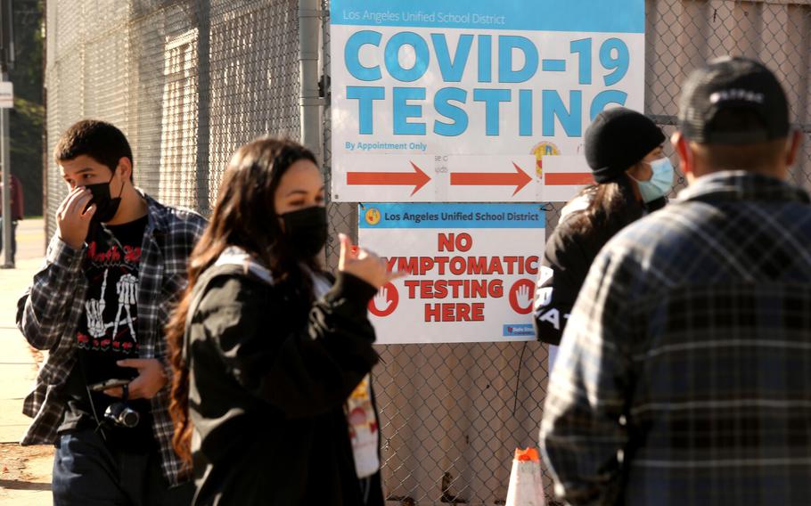 A Health Site Support worker, second from left, directs LAUSD students and staff who wait in line for a COVID-19 test at a walk-up site at the El Sereno Middle School in the El Sereno neighborhood in Los Angeles on Jan. 4, 2022.