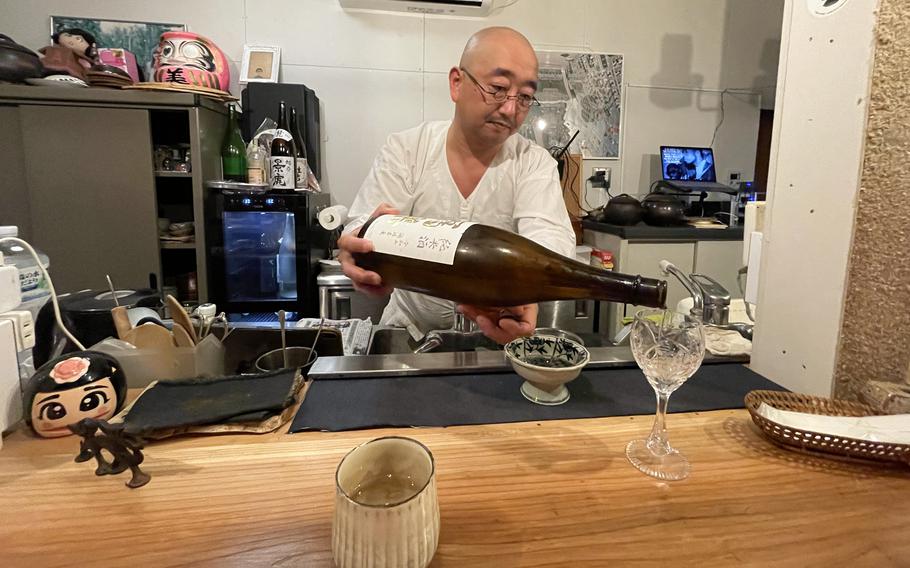 シェフの伊藤芳典が、別府にある彼の小さな飲食店であるMii Beeでの親密な食事の間に、グラス一杯の日本酒を注いでいます。