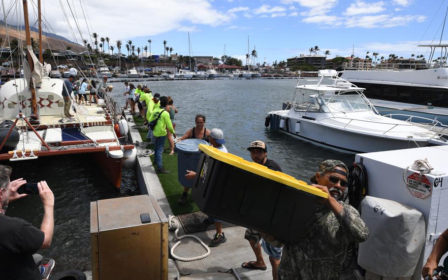 Members of the Hikianalia canoe club offload a boat with supplies at the Maalaea Harbor before heading into the burn area on Monday in Maalaea, Hawaii. The death toll continues to rise for the fires on Maui.