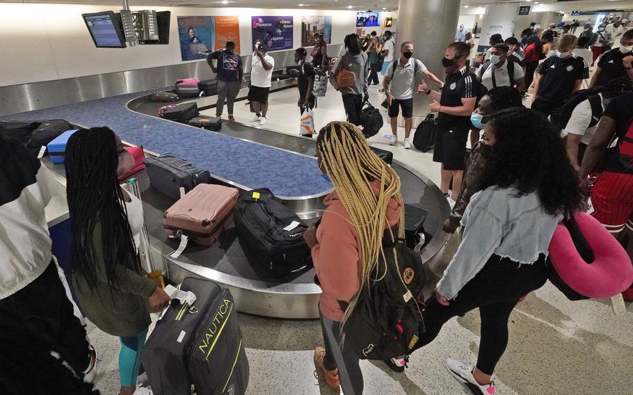 Travelers wait for their luggage at a baggage carousel at Miami International Airport on May 28, 2021.